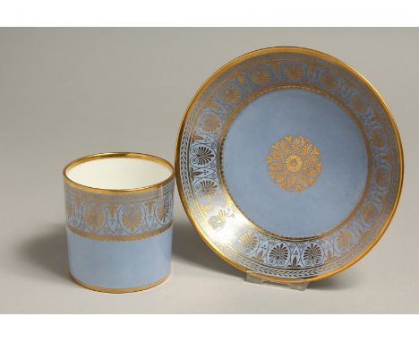 A SEVRES COFFEE CAN AND SAUCER decorated with elaborate classical gilding on a light blue ground.   Sevres blue circular mark