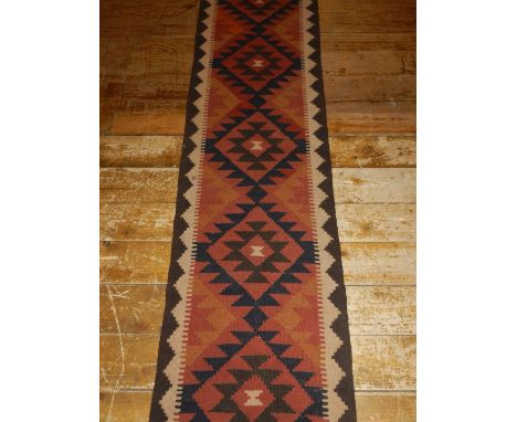 A Persian handmade Kelim runner, decorated with geometric design on red ground, fringed. L.205cm, W.55cm 
