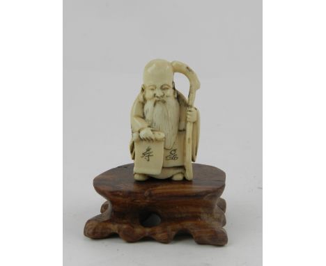 An early 20th century Japanese ivory netsuke, a study of a sage, holding a staff and scroll. Approx. H: 5cm