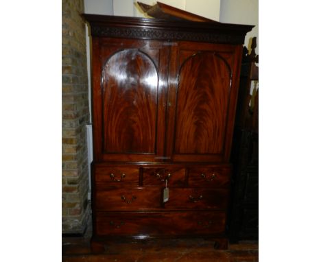 A George III mahogany linen press, having a plain moulded cornice above a blind fret cut foliate scroll frieze and two arch p