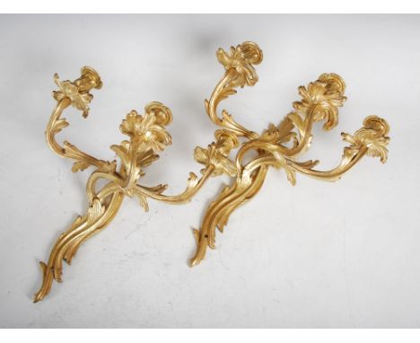 A pair of late 19th/ early 20th century gilt metal Rococo style three light wall sconces, the urn shaped nozzles with detacha