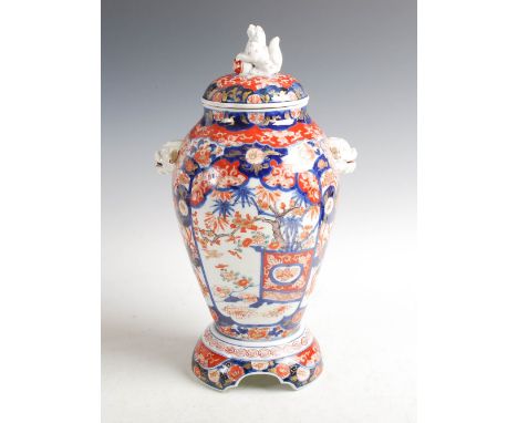 A Japanese Imari jar, cover and stand, Meiji Period, decorated with panels of urns issuing bamboo divided by panels of birds 