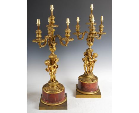 A pair of late 19th/ early 20th century French ormolu and marble four light candelabra, the urn shaped nozzles raised on foli