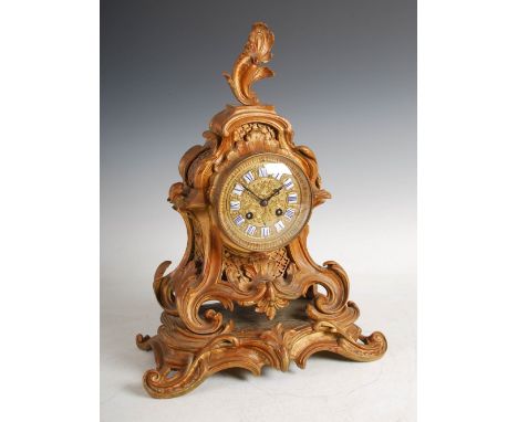 A late 19th century French Rococo style mantle clock, the circular dial with individual Roman numeral panels and twin train m