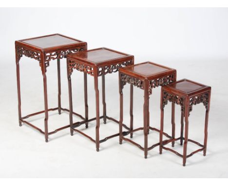 A quartetto of Chinese hardwood occasional tables, late Qing Dynasty, the square panelled tops above pierced scroll friezes c