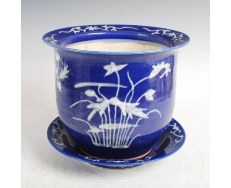 A Chinese porcelain blue ground jardiniere and stand, late Qing Dynasty, with white enamel decoration of flowers and foliage,