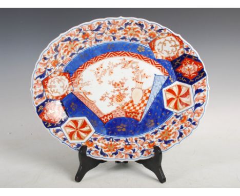 A Japanese Imari oval-shaped dish, Meiji Period, decorated with a fan-shaped panel enclosing urn issuing flowering branch sup