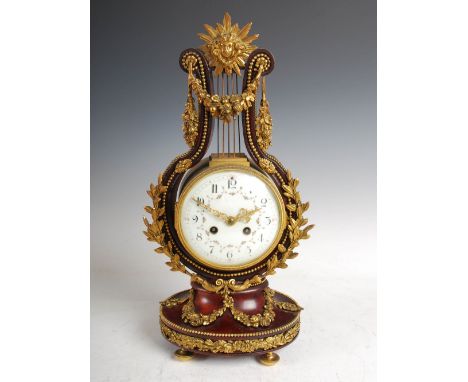 A late 19th century French mahogany and gilt metal mounted Empire style mantle clock, the slightly convex circular enamelled 