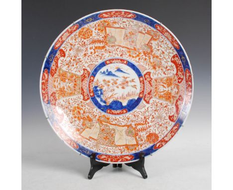 A Japanese Imari charger, Meiji Period, decorated with a central circular landscape panel within a border of peony, scrolling