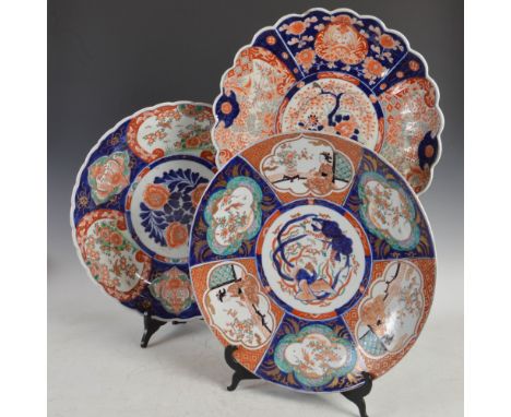 Three Japanese Imari chargers, Meiji Period, one decorated with a central panel of urn issuing flowers and foliage within a p