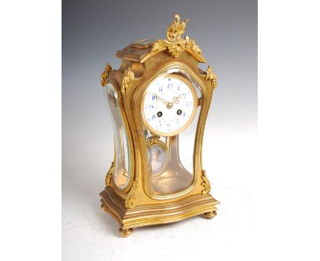 A late 19th century French Rococo style mantle clock, the circular porcelain dial with blue painted Arabic numerals and colou