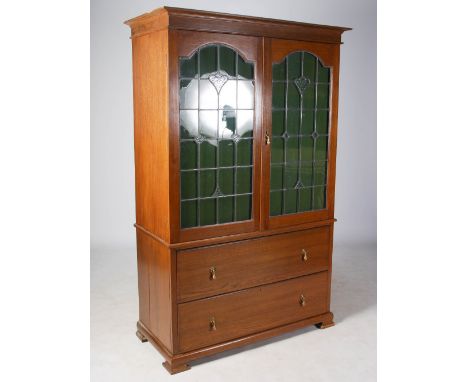 A Scottish Arts & Crafts oak and leaded glass linen press, the moulded cornice above a pair of leaded glass cupboard doors de