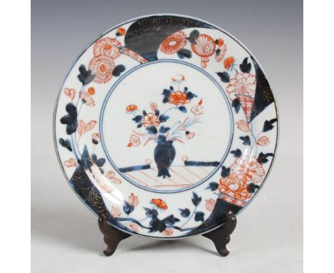 A Japanese Imari plate, Meiji Period, decorated with a circular shaped panel enclosing an urn issuing peony, within a border 