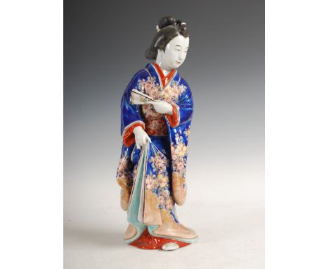 A Japanese Imari palette porcelain figure of a Bijin, Meiji Period, modelled standing holding a fan in her left hand, wearing