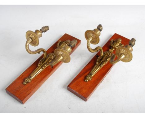 A pair of early 20th century gilt metal Neo-Classical style two light wall sconces, mounted on rectangular mahogany blocks, o