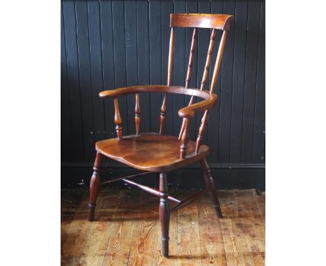 A late Georgian elm Windsor style elbow chair, with high comb back, solid seat on turned legs united by stretchers. 