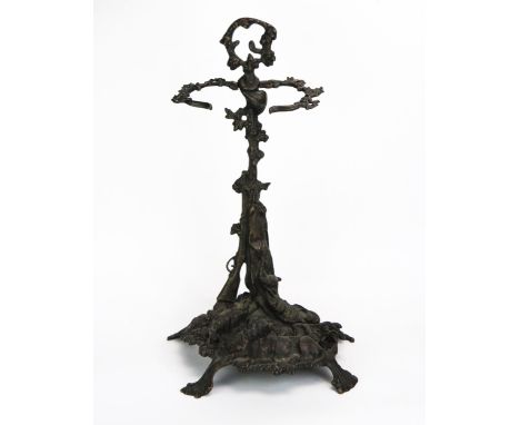 A cast metal stick stand, the foliate stem with loop handle having hunting horn, gun and dead hare decoration to a naturalist