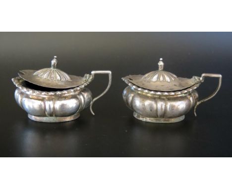 A pair of Chinese silver mustard pots, stamped marks, of lobed oval form with scroll handle and blue glass liners, 8cm long, 