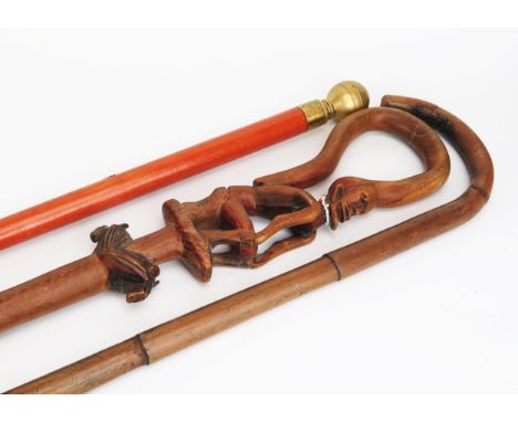 An African carved wood walking stick with seated figure and curved handle, together with two other walking sticks. 