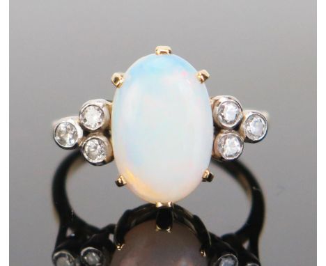 An 18ct Gold, Opal and Diamond Ring, 12.5x8.5mm central stone flanked by three c, .2mm diamonds in rub over settings, 18x12.8