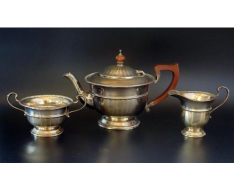 A George V silver three-piece tea service, maker Adie Brothers Ltd, Birmingham, 1931, of circular form with reeded girdle, on