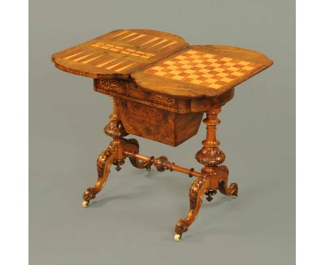 A Victorian walnut games table, with shaped edge, backgammon, cribbage and checkerboard, with frieze drawer, wooden bag benea