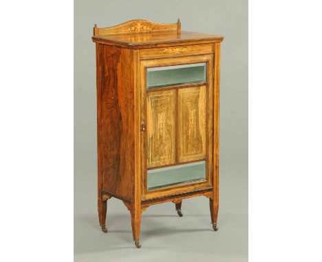 An Edwardian inlaid rosewood music cabinet, with rear upstand, mirrored and panelled door enclosing shelves and raised on tap