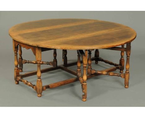 A large oak double gate leg dining table, oval in plan.  Width 71 ins, length open 79 ins. 