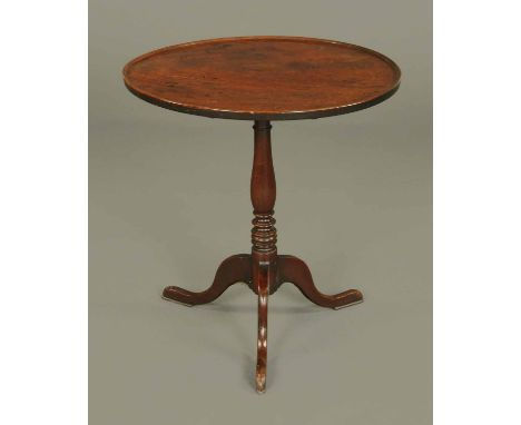 A George III mahogany tripod table, with dished top, snap action and turned column raised on three downswept legs terminating
