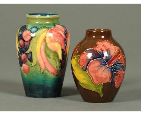 A Moorcroft vase, decorated with leaf and berry pattern to green ground, and another with brown ground.  Heights respectively
