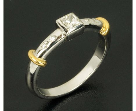 An 18 ct gold rubover set diamond ring, with princess cut centre diamond and round diamonds to each shoulder, size O/P. CONDI