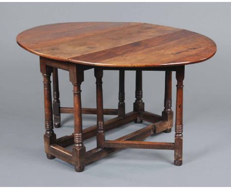 A Georgian oak gate legged dining table, oval in plan, with single gate to either end being turned and united by a series of 