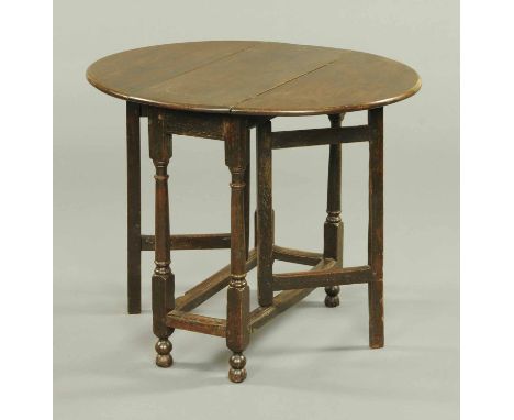 A small antique oak gate leg table, oval in plan, with turned legs and moulded stretchers.  Width 28 ins. 