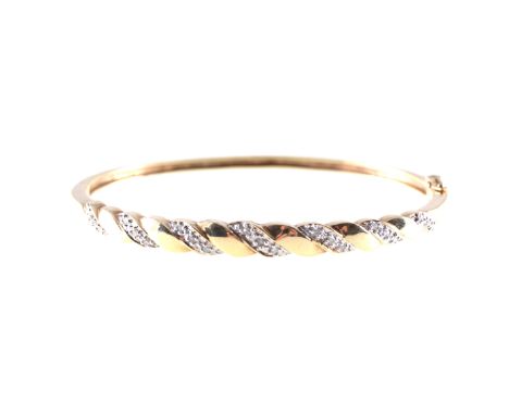 A diamond set half hinged bangle, the 5mm wide yellow and white metal bangle set with twenty-one diamonds in a diagonal desig