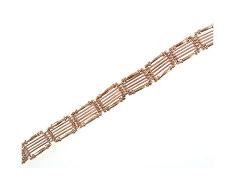 A yellow metal bracelet, 10mm wide six bar gate design, the central bars plain and outer bars crimped, fitted with a box snap