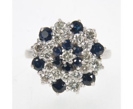 A sapphire and diamond multi stone cluster ring, twelve sapphires and nineteen diamonds claw set in an all white metal circul