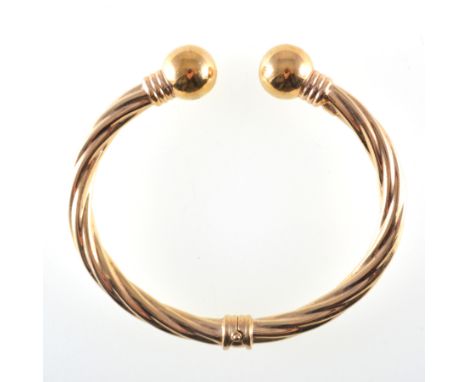 A 9 carat yellow gold torque bangle, 5.mm wide hollow twisted rope design with central hinge and 12mm polished bead terminati