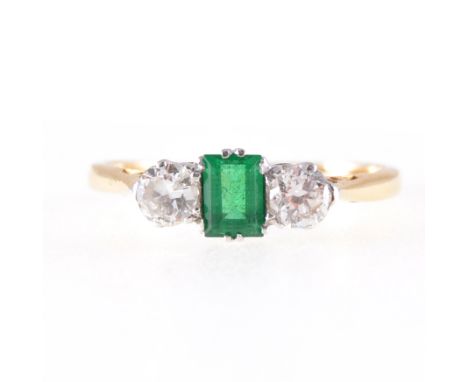 An emerald and diamond three stone ring, a rectangular step cut emerald 4.3mm x 3.2mm, with a brilliant cut diamond to each s