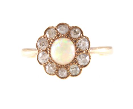 An opal and diamond circular cluster ring, a 5mm round cabochon cut opal surrounded by ten old cut diamonds milgrain set in a