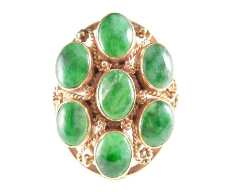 A green stone dress ring, the seven cabochon cut untested stones individually collet set in an all yellow metal mount with tw