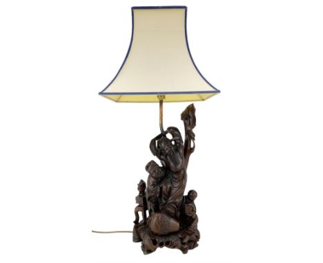 20th century Chinese carved hardwood table lamp, modelled as a sage with two attendants peering on either side, his foot rest