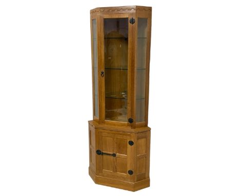 Mouseman - oak corner cabinet, penny moulded cresting rail over bevelled glazed cabinet enclosed by single door, fitted with 