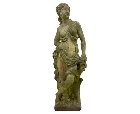 Weathered cast stone statue, in the form of a classical nymph wearing scantily draped clothing, holding a posy of flowers and