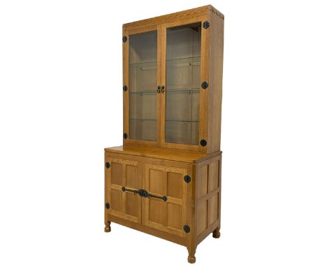 Mouseman - oak floor-standing glazed display cabinet on cupboard, raised cabinet enclosed by two bevelled glazed doors, the l