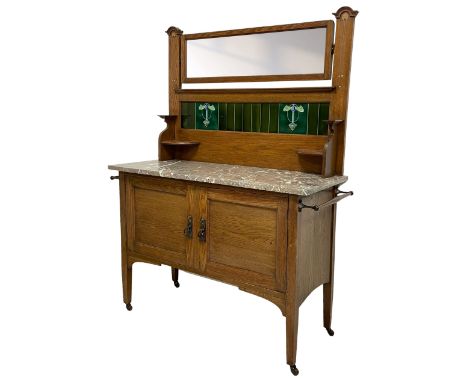 Arts & Crafts oak washstand, the raised back with rectangular bevelled mirror over green glazed tiles with stylised floral de