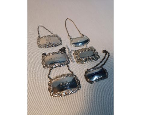 A selection of six drinks labels, to include four silver hall marked. Included in the silver lot is a blue enamel Sherry labe