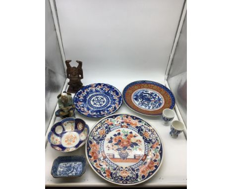 Imari style Japanese plates, with two egg cups a two small oriental dishes and two figures, one made out of carved hard wood,