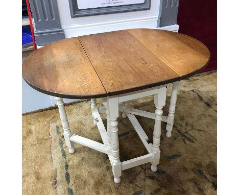 A Solid light oak topped, drop end dining table. Painted white base leg supports. Fully extended it measures 75x104x75.5cm 