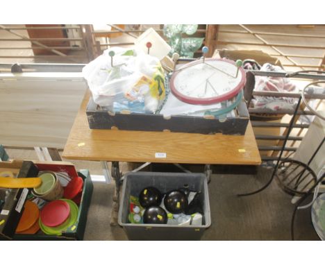 A wooden topped table with cast iron base, a box containing wall clock, various light bulbs and another box with three bowlin