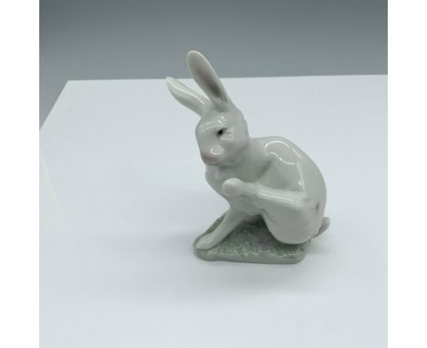 Glossy figure of a cute bunny stretching their leg up to get a scratch in. Lladro backstamp. This item has its original box. 
